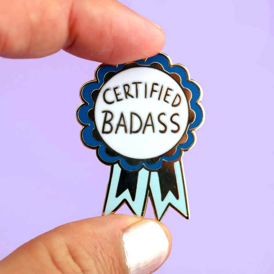 Fingers holding Certified Badass Lapel Pin