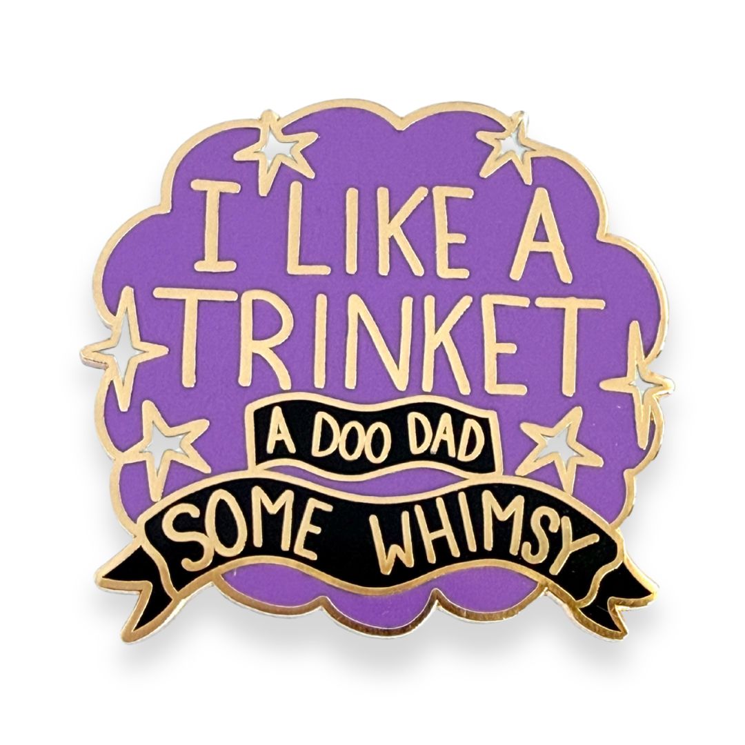 Purple and gold enamel pin with I like a trinket, a doo-dad, some whimsy design on a cloud background