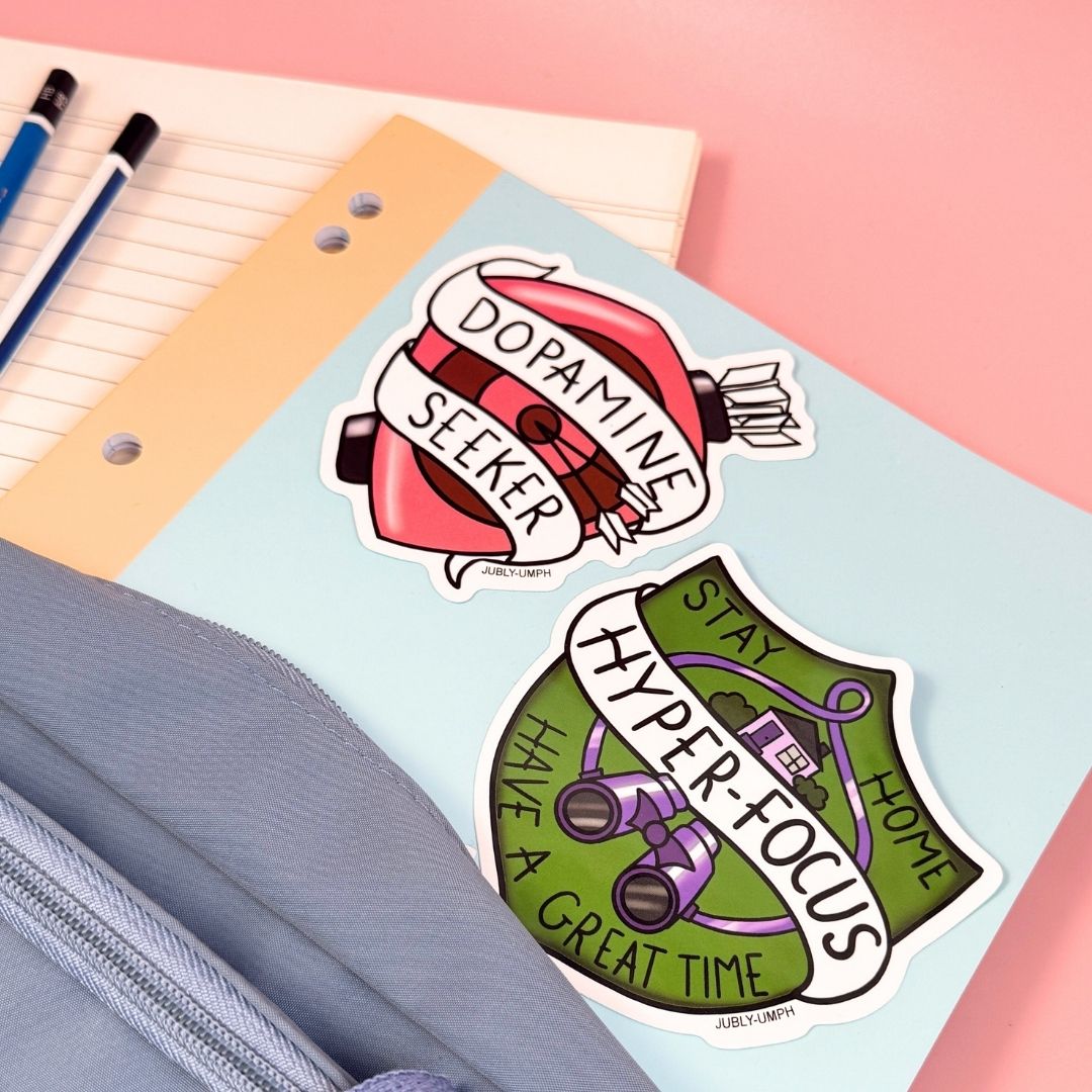 Two colorful stickers on a notebook with stationery items.