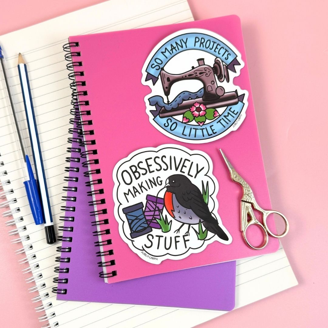 Pink notebook with sewing-themed stickers on a pink background